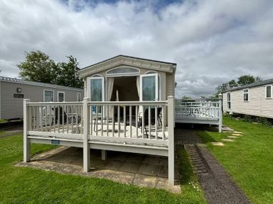 a holiday caravan with a deck and seating area at Butlins Skegness - Holiday Accommodation 22071 in Ingoldmells