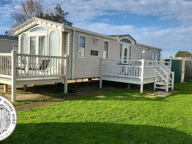 a mobile home with a deck and grass area at Butlins Skegness - Holiday Accommodation 22071 in Ingoldmells