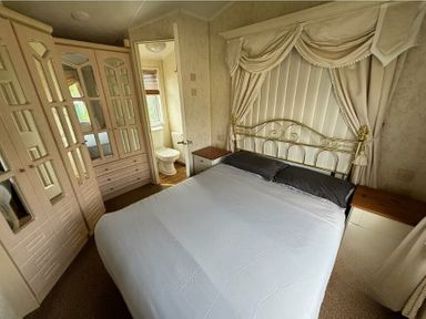 a bedroom with a bed, a mirror wardrobe, and a bathroom in Butlins Skegness - Holiday Accommodation 22071, Ingoldmells