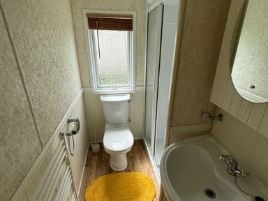 a bathroom with a toilet, sink, shower, and a window at Butlins Skegness - Holiday Accommodation 22071 in Ingoldmells