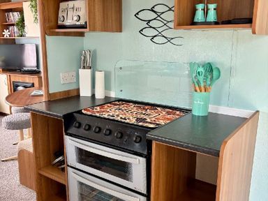 a kitchen area with an oven, countertop, and utensils at Valley Farm Holiday Park - Holiday Accommodation 22153, Clacton-on-Sea