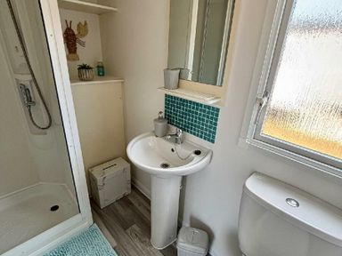 a bathroom with a sink, shower, mirror, and window at Valley Farm Holiday Park - Holiday Accommodation 22153 Clacton-on-Sea