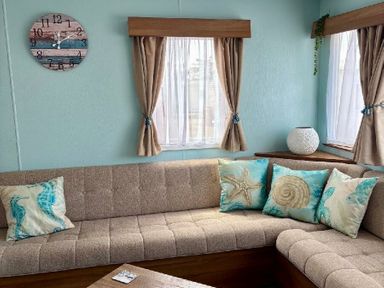 a seating area with a brown couch and decorative cushions at Valley Farm Holiday Park - Holiday Accommodation 22153 Clacton-on-Sea