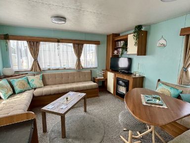 a living room with a sofa, television, and dining table at Valley Farm Holiday Park - Holiday Accommodation 22153 Clacton-on-Sea