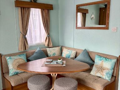 a seating area with a round table and cushioned bench at Valley Farm Holiday Park - Holiday Accommodation 22153 Clacton-on-Sea