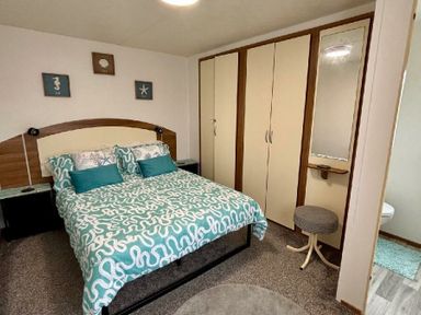 a bedroom with a bed, wardrobe, and mirror at Valley Farm Holiday Park - Holiday Accommodation 22153 in Clacton-on-Sea