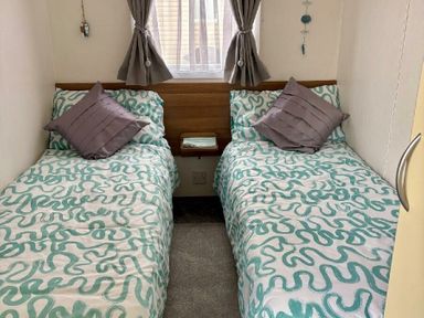 a bedroom with two single beds featuring patterned bedding and pillows at Valley Farm Holiday Park - Holiday Accommodation 22153, Clacton-on-Sea