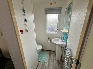 a bathroom with a toilet, sink, and a mirror at Valley Farm Holiday Park - Holiday Accommodation 22153 Clacton-on-Sea