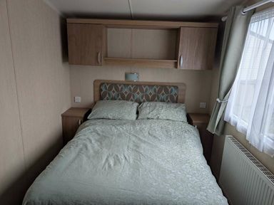 a bedroom with a double bed and cabinets at Ty Gwyn Caravan Park - Holiday Accommodation 22189 in Abergele