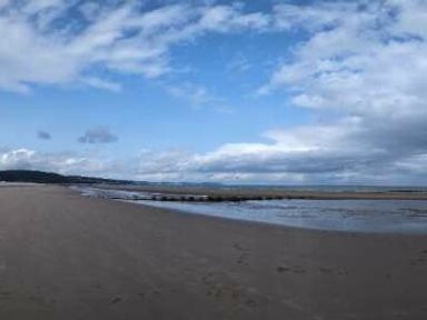 a beach with sand and water under a cloudy sky at Ty Gwyn Caravan Park - Holiday Accommodation 22189, Abergele
