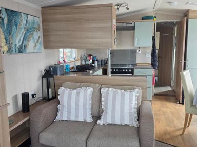 A living room with a sofa and kitchen area at Ty Gwyn Caravan Park - Holiday Accommodation 22189 Abergele