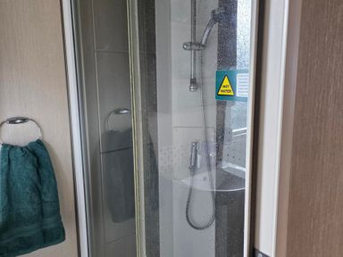 A shower with a towel hanging in the bathroom at Ty Gwyn Caravan Park - Holiday Accommodation 22189 Abergele