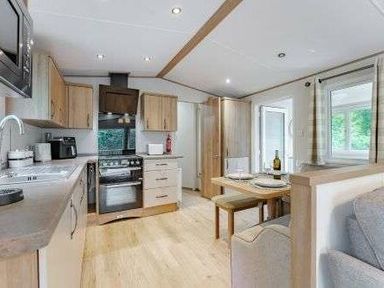 a kitchen area with wooden cabinetry and a dining table at Kelling Heath Holiday Park - Holiday Accommodation 22244, Holt