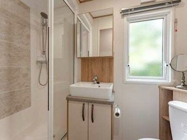 a bathroom with a shower, sink, mirror, and cabinet at Kelling Heath Holiday Park - Holiday Accommodation 22244 in Holt