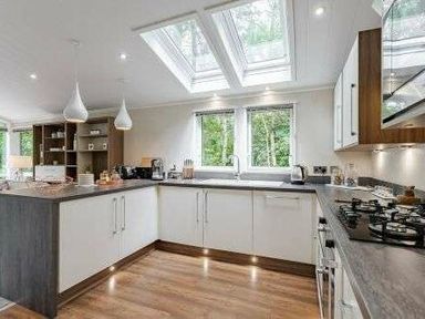 a kitchen with skylights, modern cabinets, and a countertop at Kelling Heath Holiday Park - Holiday Accommodation 22249, Holt