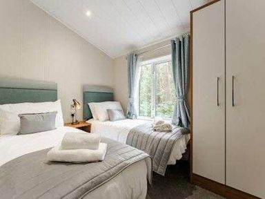 a bedroom with two single beds and a wardrobe at Kelling Heath Holiday Park - Holiday Accommodation 22249 in Holt