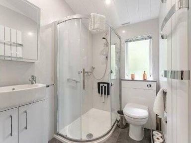 a bathroom with a glass shower, sink, and toilet at Kelling Heath Holiday Park - Holiday Accommodation 22249 in Holt