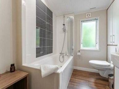 a bathroom with a bathtub, shower, and toilet at Kelling Heath Holiday Park - Holiday Accommodation 22249, Holt