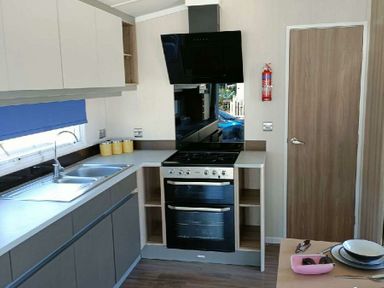 a kitchen with a sink, stove, and countertop at Lyons Winkups and Primrose - Holiday Accommodation 22330, Towyn