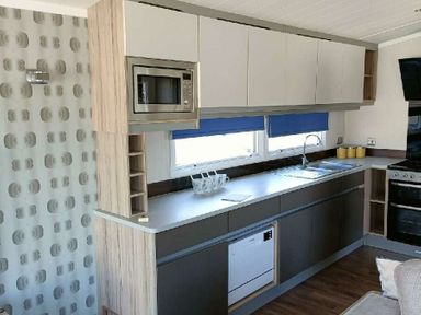 a kitchen area featuring cabinets, a sink, a built-in microwave, and a dishwasher at Lyons Winkups and Primrose - Holiday Accommodation 22330 Towyn