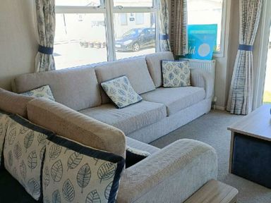 a living room with a beige sectional sofa and leaf-patterned cushions at Lyons Winkups and Primrose - Holiday Accommodation 22330 Towyn