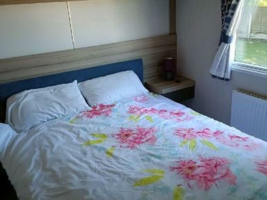 a bedroom with a bed featuring a floral bedspread and a window at Lyons Winkups and Primrose - Holiday Accommodation 22330 Towyn