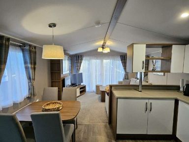 a living area with a dining table and chairs, a seating area, and a TV at Aberdunant Hall Holiday Park - Holiday Accommodation 22358, Porthmadog