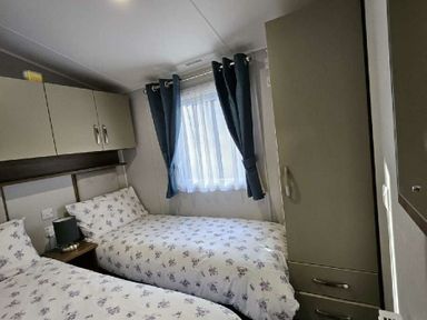a bedroom with two single beds and a window at Aberdunant Hall Holiday Park - Holiday Accommodation 22358 in Porthmadog