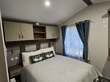 a bedroom with a double bed and window curtains at Aberdunant Hall Holiday Park - Holiday Accommodation 22358 in Porthmadog