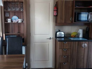 a kitchen area with cabinets, a microwave, a toaster, and a door at Waterside, Paignton - Holiday Accommodation 2287, Paignton