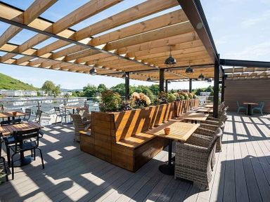 a covered outdoor seating area with wooden furniture and plants at Waterside, Paignton - Holiday Accommodation 2287, Paignton