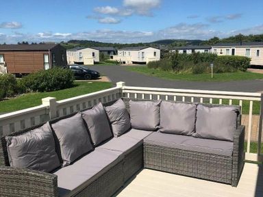 a patio area with a sectional sofa overlooking a holiday park at Lakeland Leisure Park - Holiday Accommodation 3166 Flookburgh