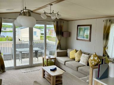 a living room with a sofa and sliding glass doors at Lakeland Leisure Park - Holiday Accommodation 3166 Flookburgh