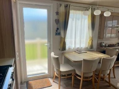 a dining area with a table and chairs next to a door with a window at Lakeland Leisure Park - Holiday Accommodation 3166 Flookburgh