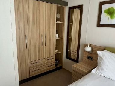 a bedroom corner with a wardrobe, bedside table, and mirror at Lakeland Leisure Park - Holiday Accommodation 3166 in Flookburgh