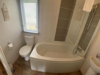 a bathroom with a bathtub, shower, toilet, and window at Lakeland Leisure Park - Holiday Accommodation 3166 Flookburgh