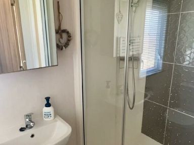 a bathroom with a shower, sink, and mirror at Lakeland Leisure Park - Holiday Accommodation 3166, Flookburgh