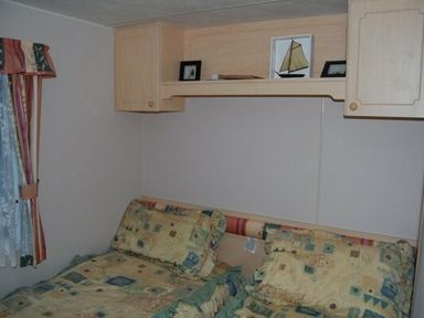a bedroom with two beds and shelves containing photos at Edwards Leisure Park - Holiday Accommodation 318, Towyn