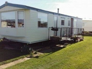 a mobile home with a front deck on grass at Edwards Leisure Park - Holiday Accommodation 318 Towyn