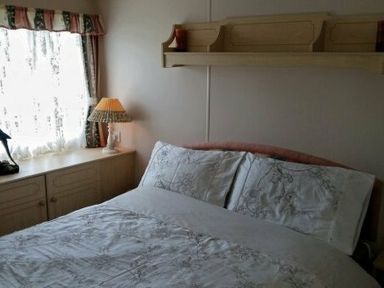 a bedroom with a double bed and a lamp on a bedside table at Edwards Leisure Park - Holiday Accommodation 318 Towyn
