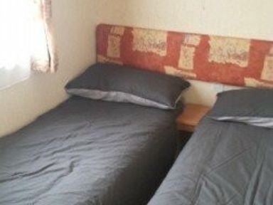 a bedroom with two single beds and a bedside table at Seven Bays Park (Maribou) - Holiday Accommodation 3966, St Merryn
