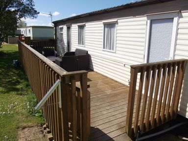 a wooden deck with a railing leading to a mobile home at Seven Bays Park (Maribou) - Holiday Accommodation 3966, St Merryn