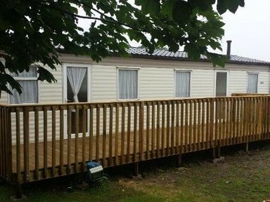 a static caravan with a wooden deck at Seven Bays Park (Maribou) - Holiday Accommodation 3966 St Merryn