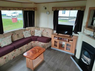 a living room with a curved sofa, television, and wooden coffee table at Seven Bays Park (Maribou) - Holiday Accommodation 3966 St Merryn