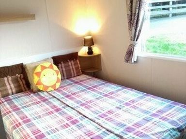 a bedroom with a double bed and a lamp on a nightstand at Swanage Bay View - Holiday Accommodation 464, Swanage