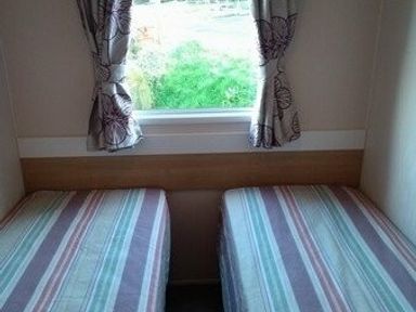 a bedroom with two single beds and a window with curtains at Swanage Bay View - Holiday Accommodation 464 in Swanage