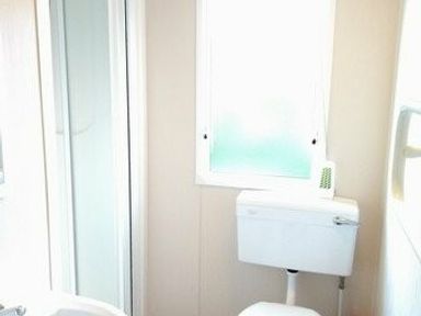 a bathroom with a toilet, shower, and window at Swanage Bay View - Holiday Accommodation 464 in Swanage