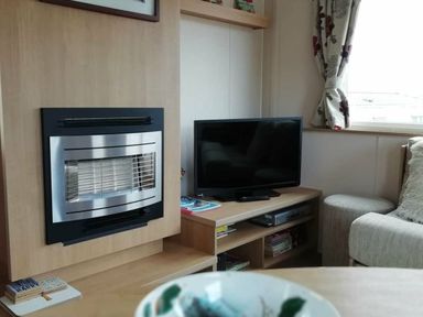 a living room with a fireplace and a television at Swanage Bay View - Holiday Accommodation 464, Swanage
