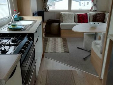 a kitchenette with a stove and dining area in Swanage Bay View - Holiday Accommodation 464, Swanage