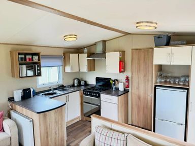 a kitchen area with cabinets, a stove, and a refrigerator at St Andrews Holiday Park - Holiday Accommodation 609 in St. Andrews